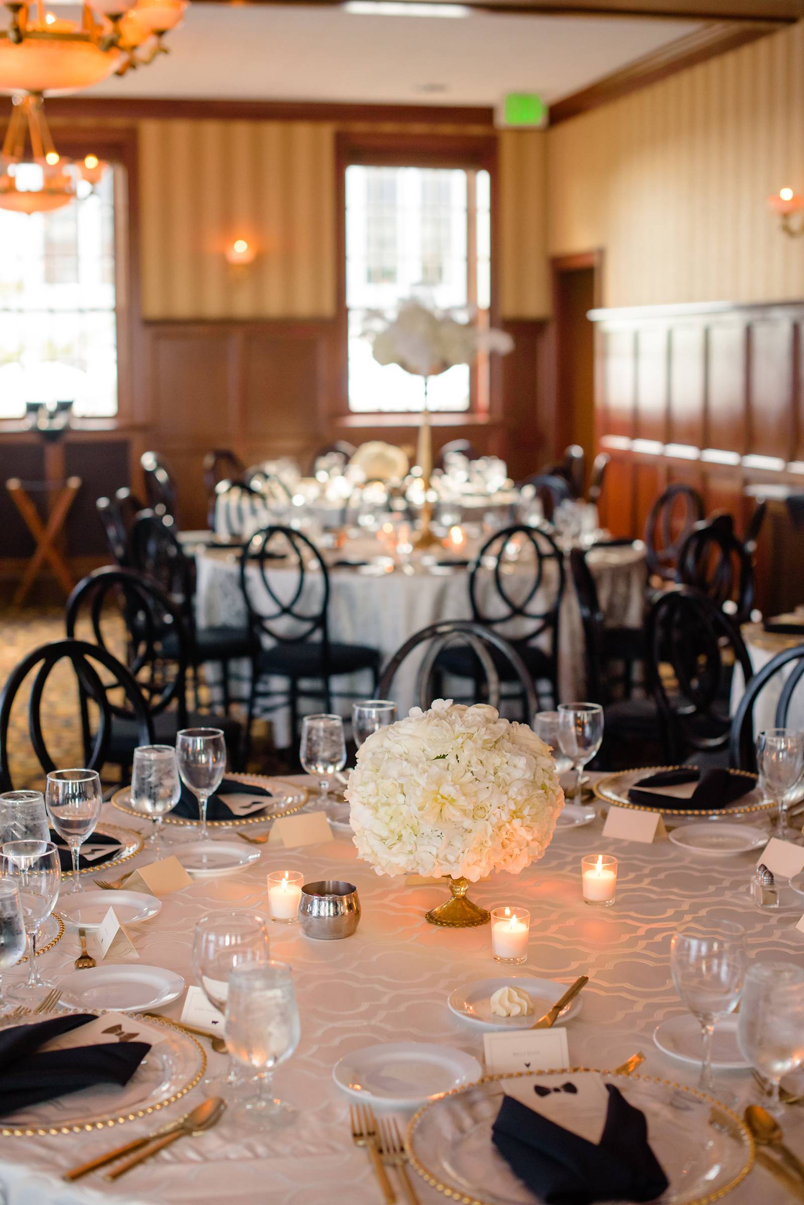 old hollywood glam modern wedding reception tables, white floral centerpieces, black infinity chairs