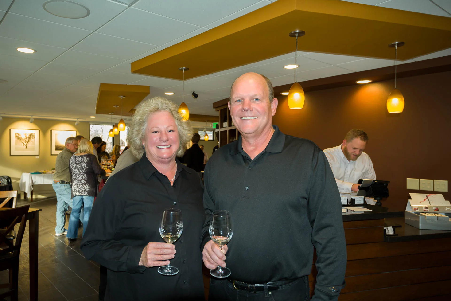 A smiling couple enjoys a white wine tasting inside the modern and cozy Cambridge Winery Madison tasting room during a private wedding event.