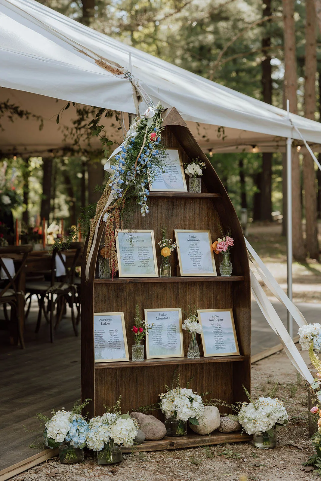 Wedding reception seating chart displayed on a wooden boat shelf with lake-themed table names
