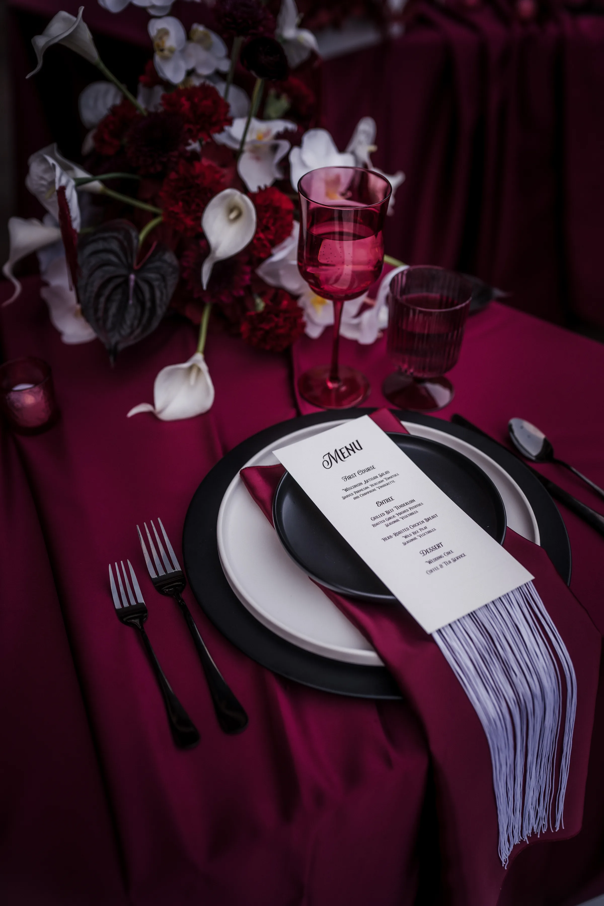 custom wedding menus from LK Bridal Studio with western tassels placed on layered plates and linens at a reception table 