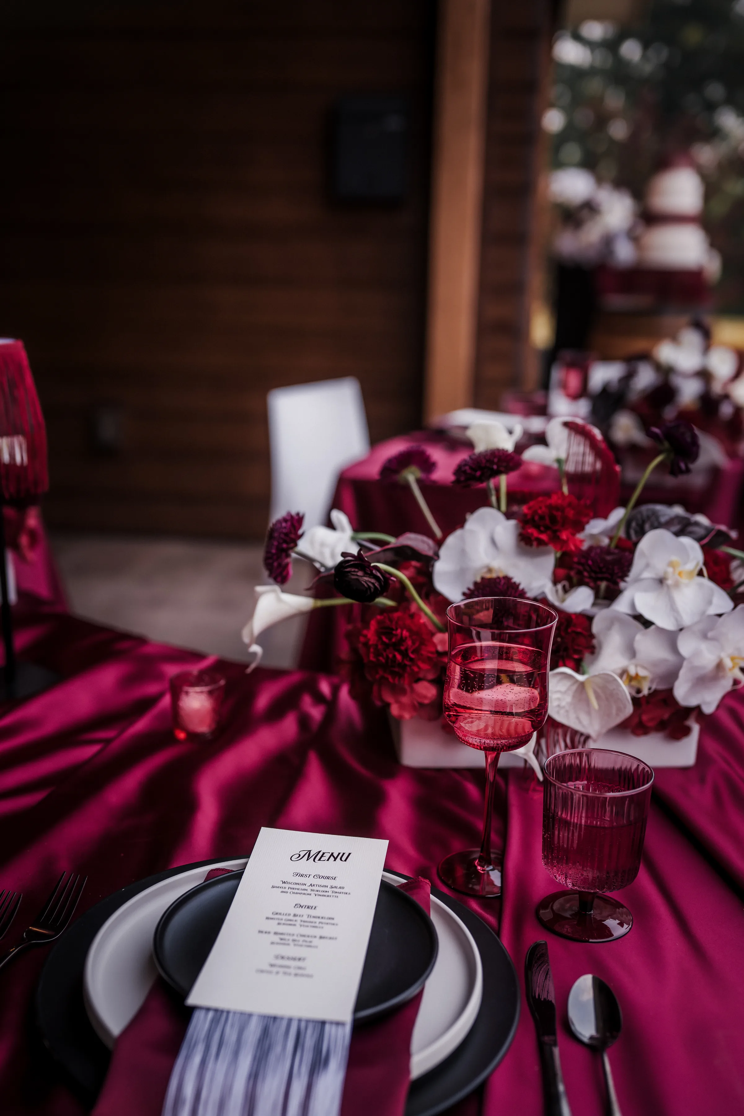 a detail photo of a custom menu, tinted crystal glassware, and moody modern cowboy wedding floral centerpieces at Barnwood Events