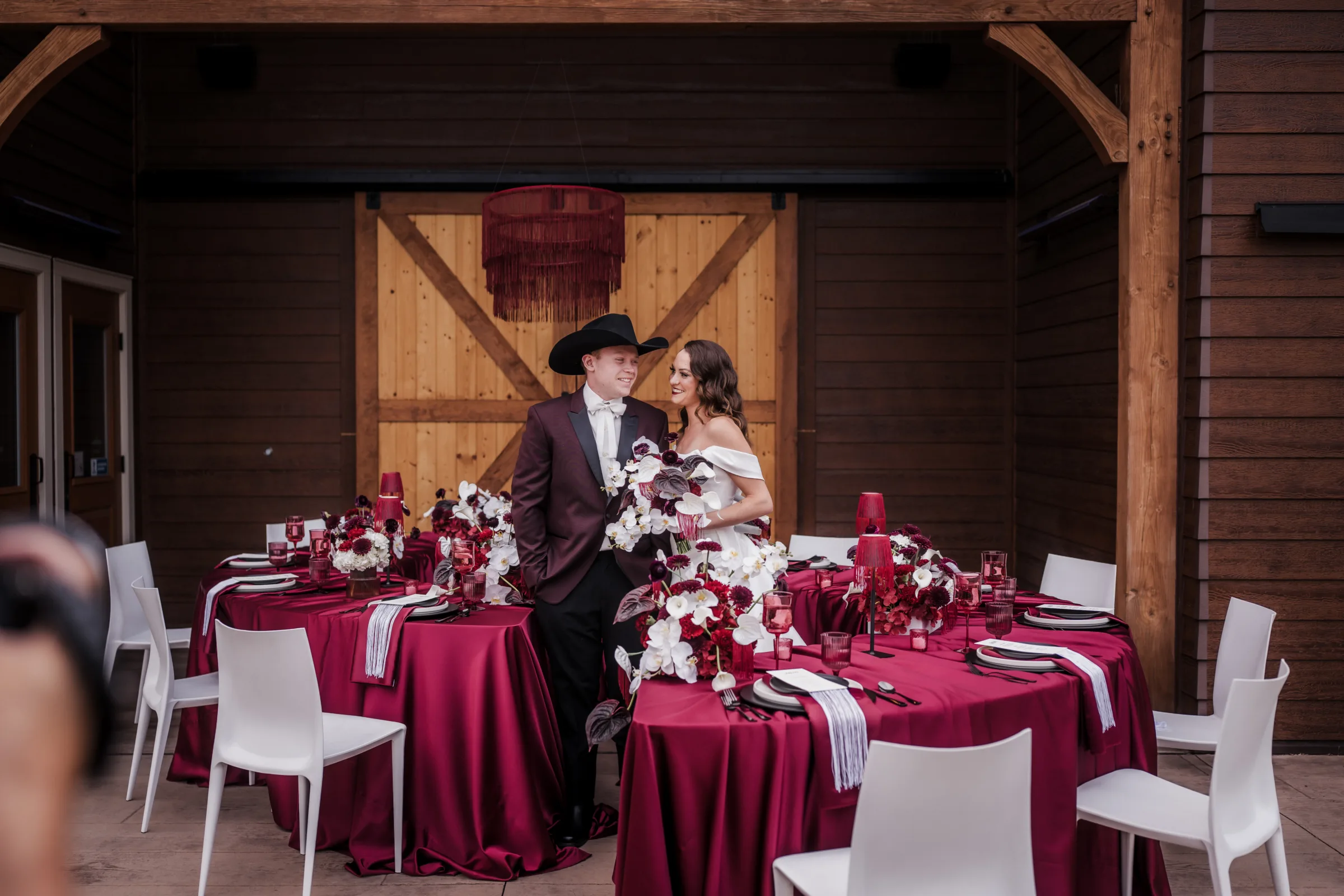 a bride and groom stand between reception tables at a moody modern cowboy wedding at Barnwood Events