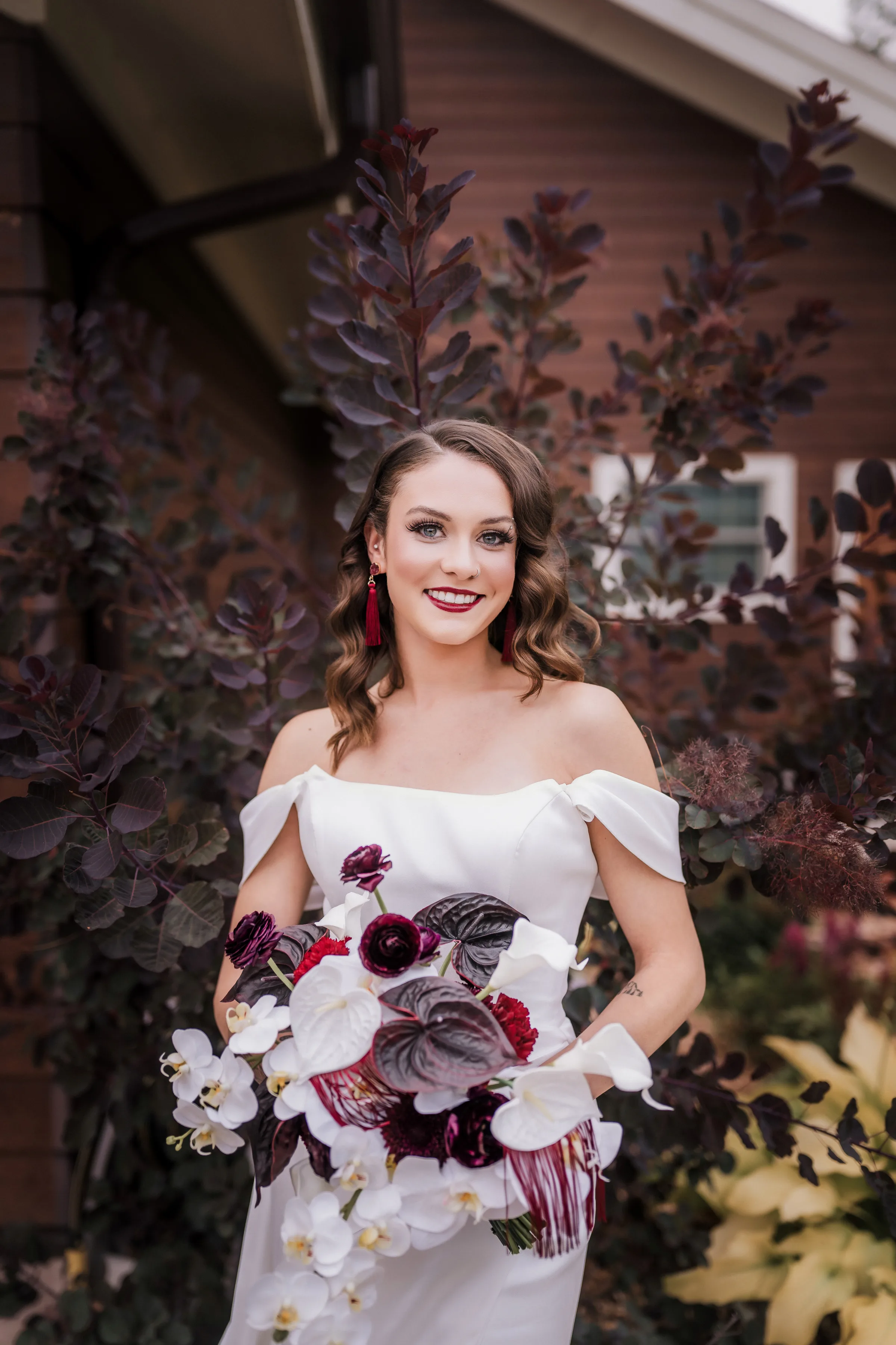 a bride wearing a dress from Charlotte's Bridal & Formal Wear, smiling, and holding a bouquet from Melody Rose Designs
