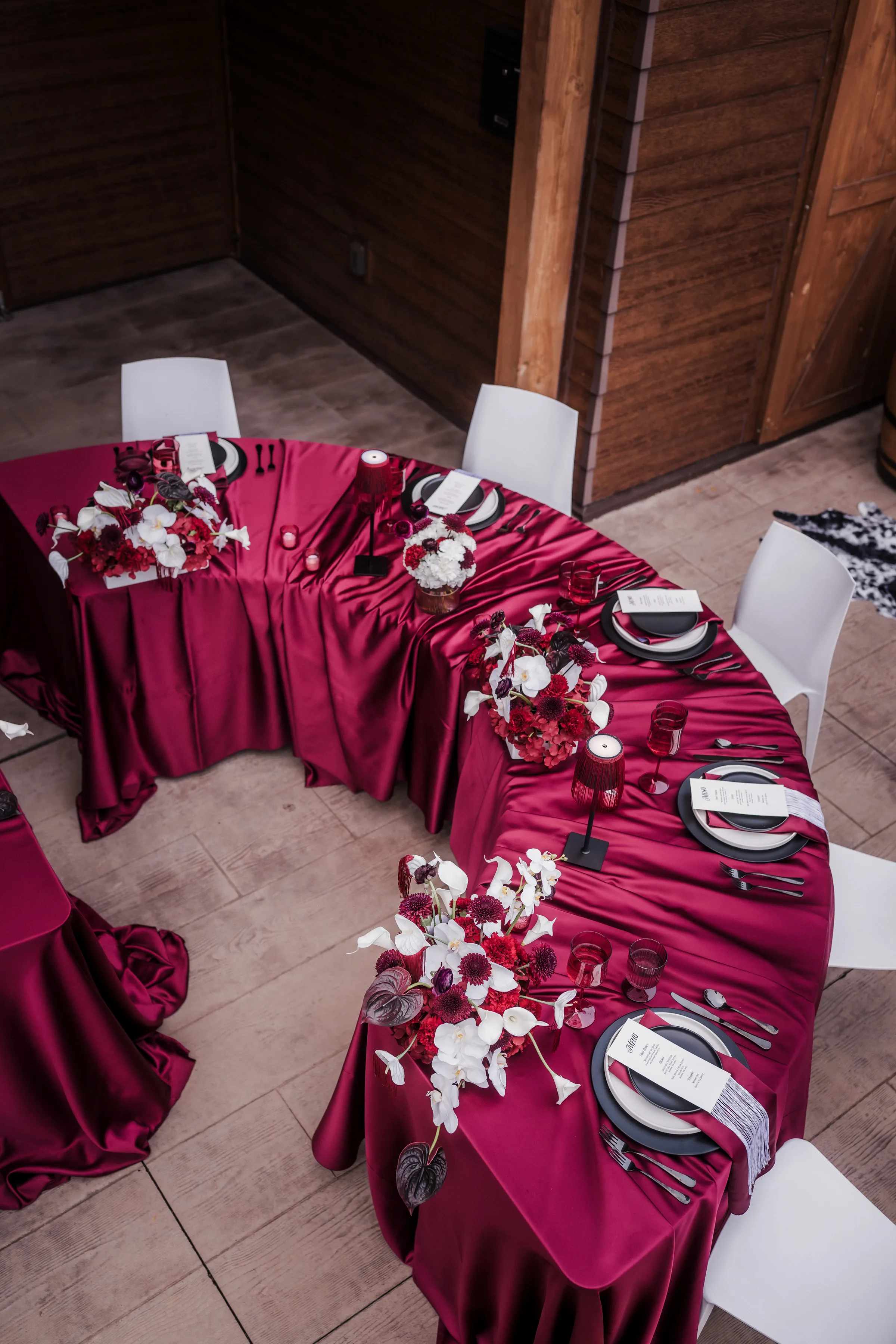 a round wedding reception table draped in burgundy velvet tablecloths and rental pieces from Event Essentials and florals from Melody Rose Designs