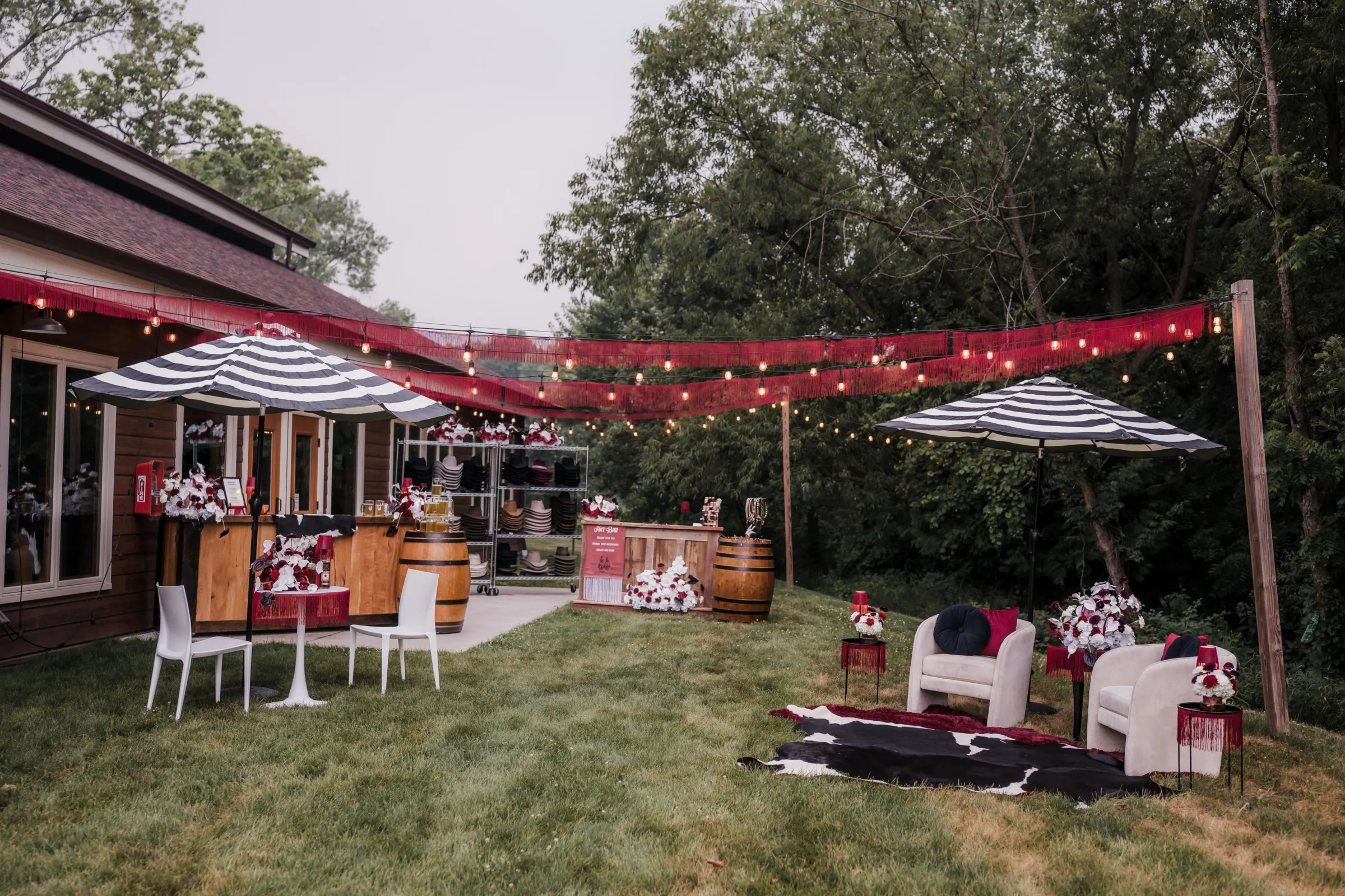 outdoor wedding lounge inspiration at Barnwood Events showing furniture rentals, umbrella seating, bar offerings, and a hat bar from Hangman Hats