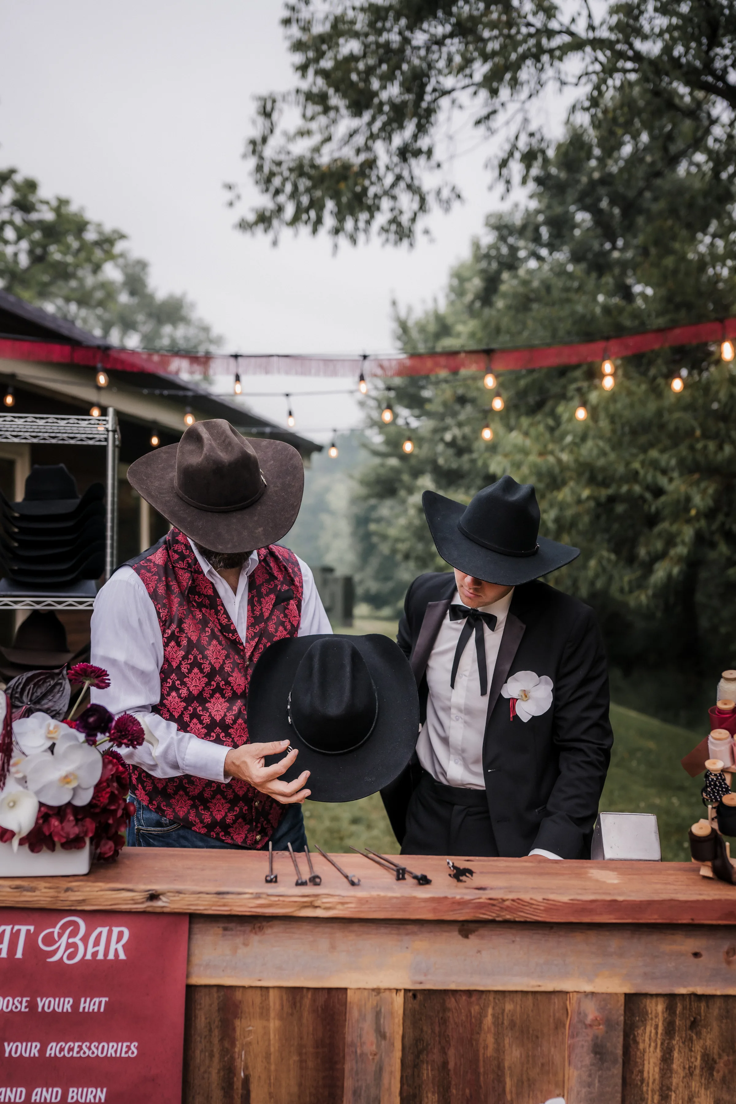 a groom model and wedding guest look over a cowboy hat offerings and accessories from Hangman Hats at a modern cowboy wedding inspiration in Wisconsin