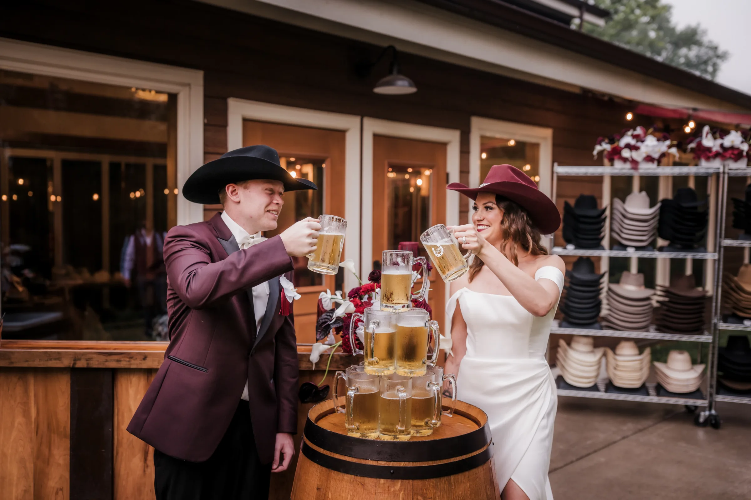 smiling bride and groom models prepare to pour beer into the top of a beer tower at a modern cowboy themed wedding on the outdoor patio at Barnwood Events in Madison, Wisconsin