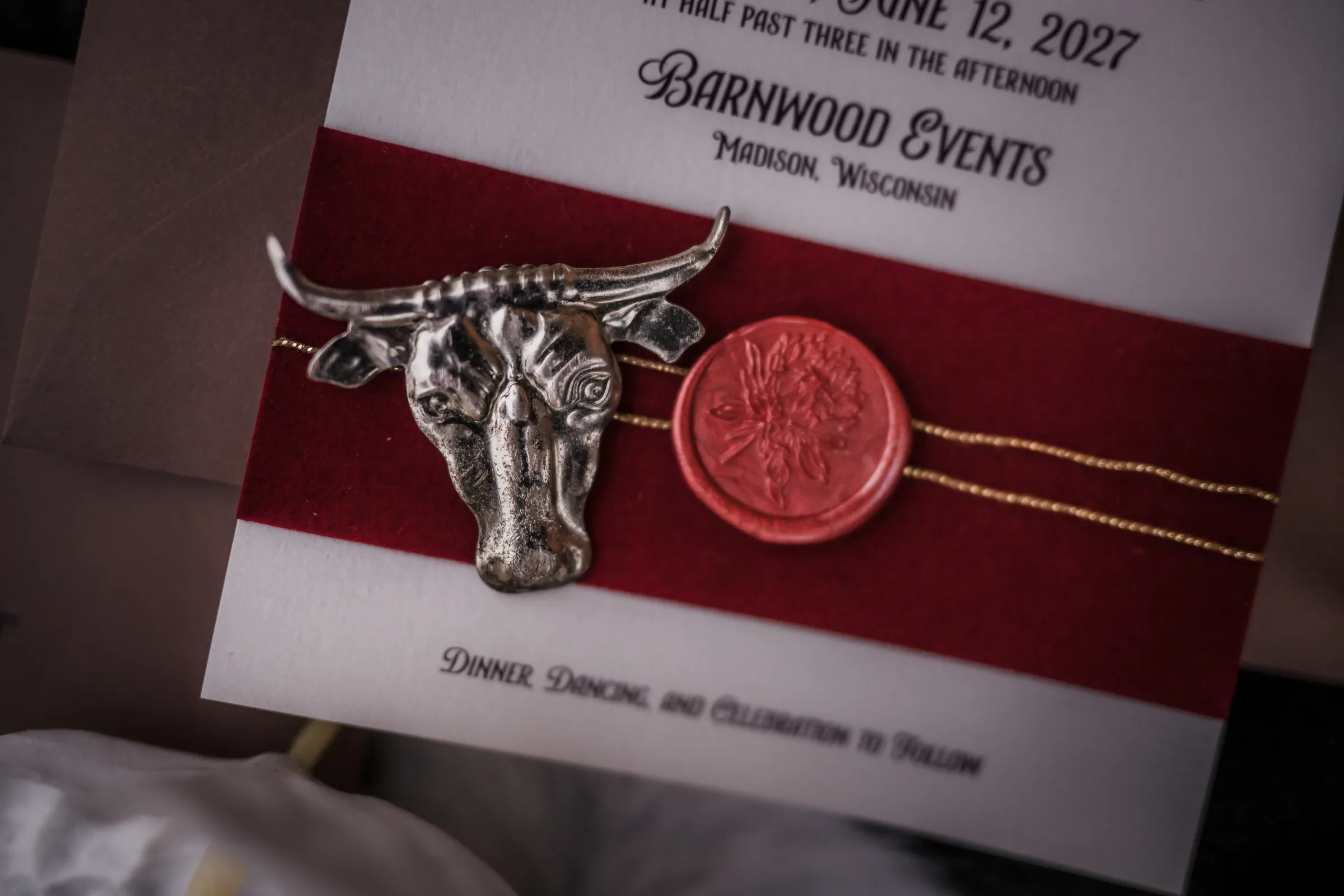 a close-up photo of a wax seal presented next to a silver cow head belt or jewelry piece