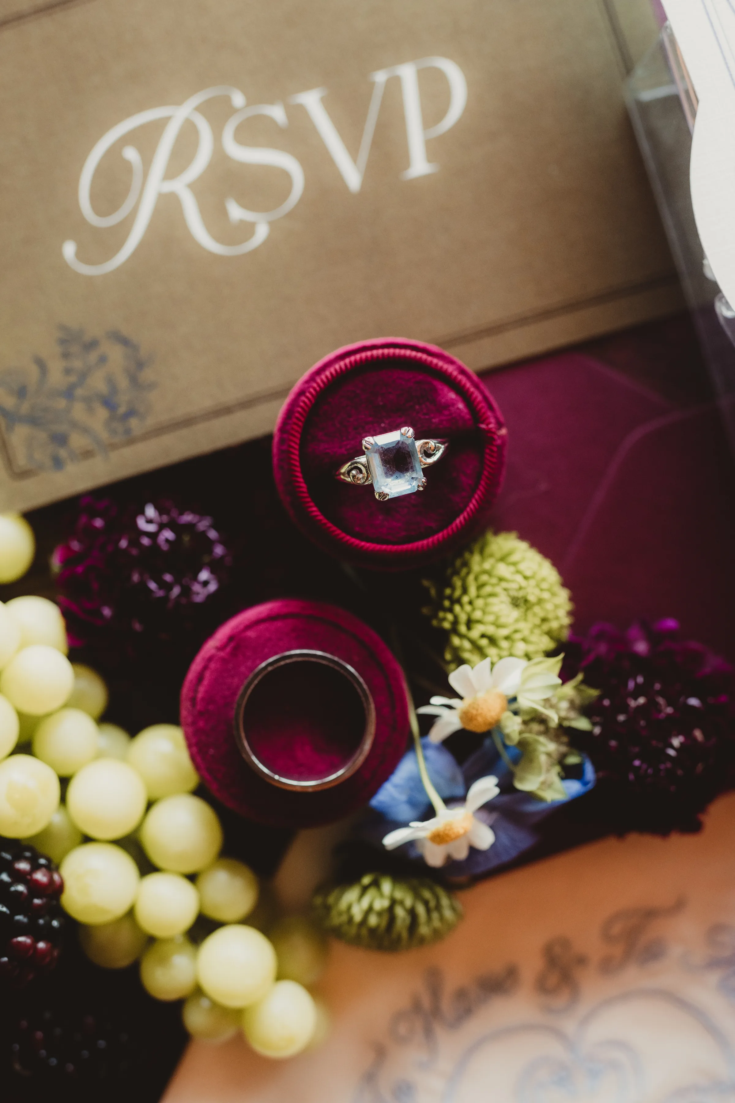 a close-up of the spiced garden party stationery suite, focusing on a princess-cut wedding ring in a burgundy ring holder