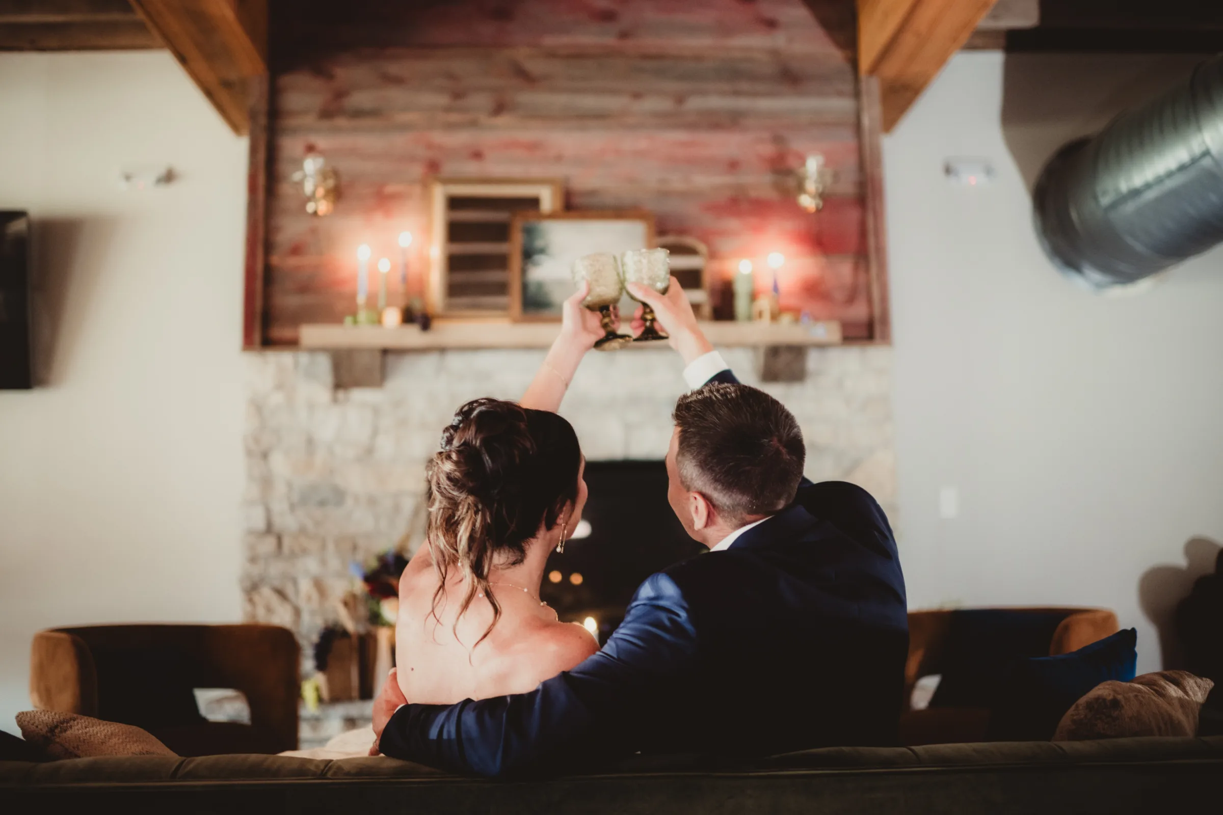 the couple sits inside, toasting glasses in front of Vennebu Hill's fireplace