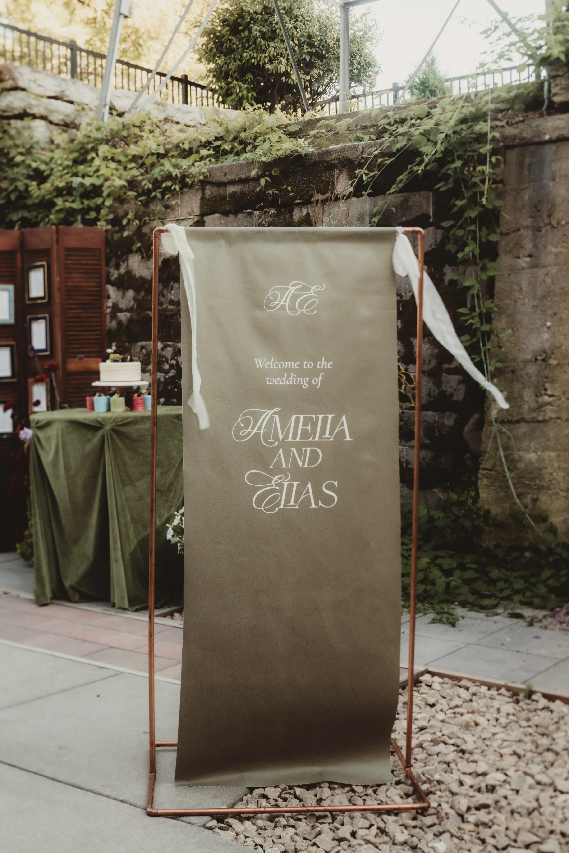 a green, draped wedding welcome sign with white lettering by LK Bridal Studio