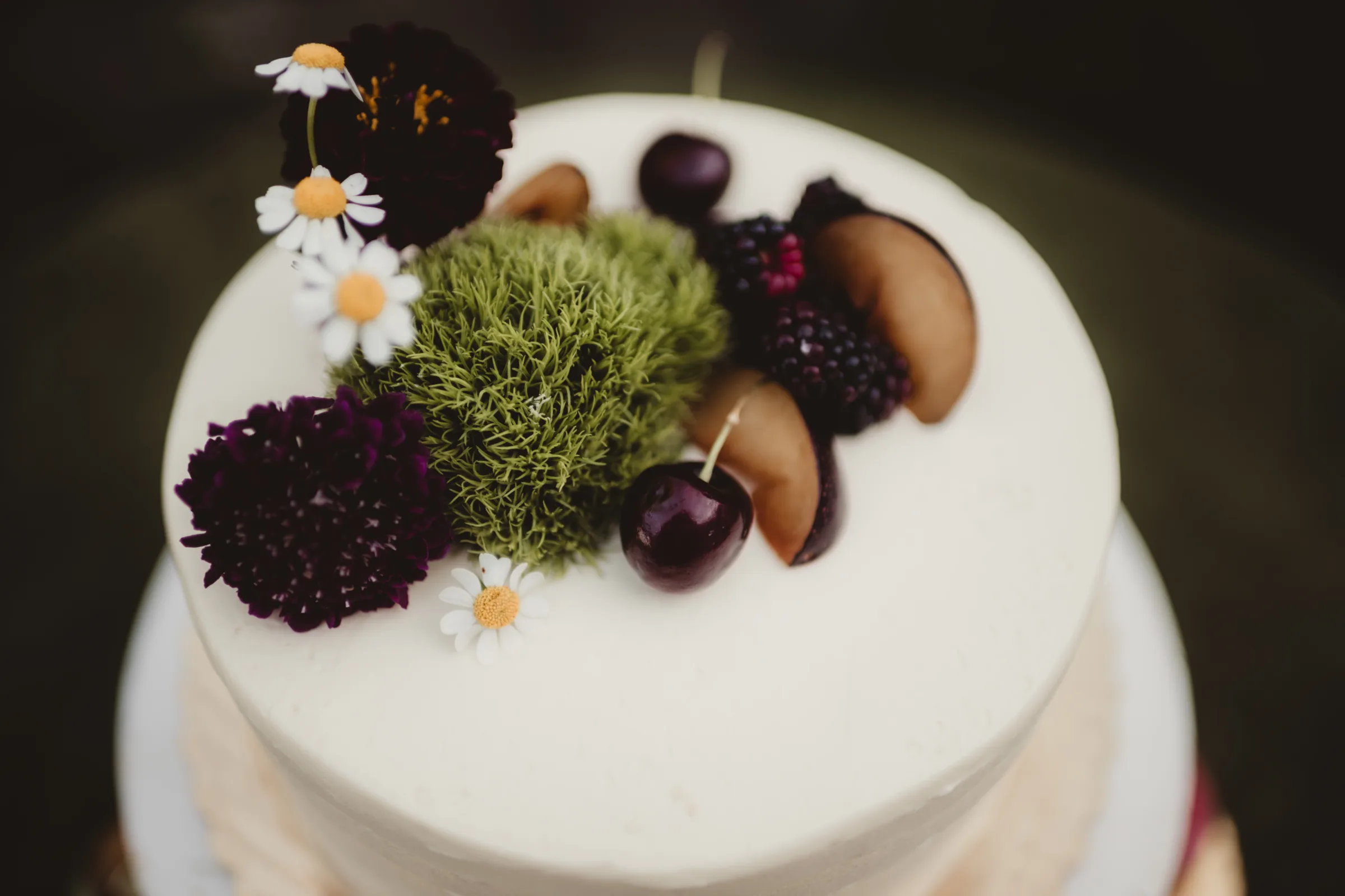 a single tier white wedding cake from Sandy Kakes topped with fruit and florals