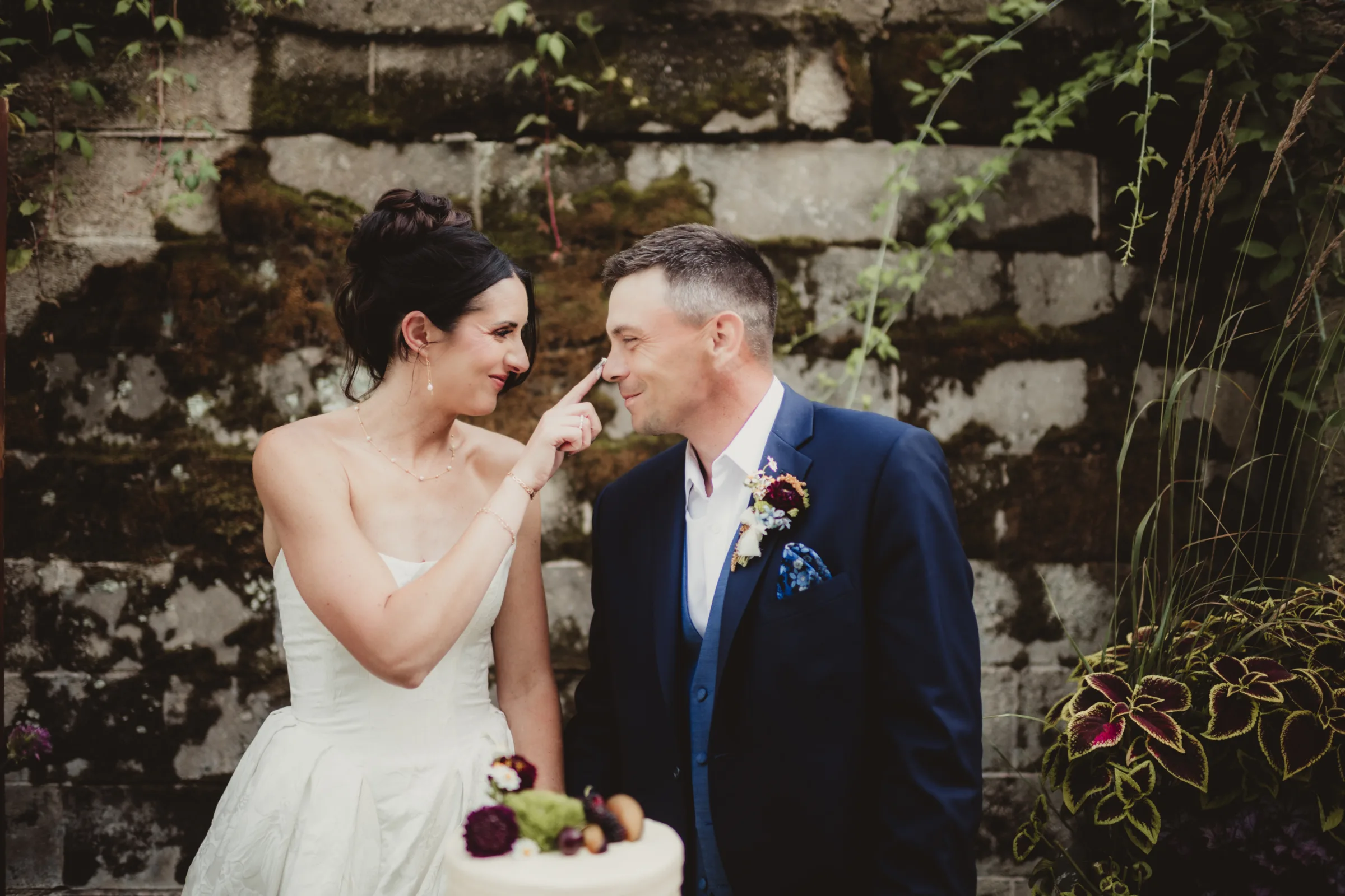 the bride model playfully wipes frosting on the groom model's nose