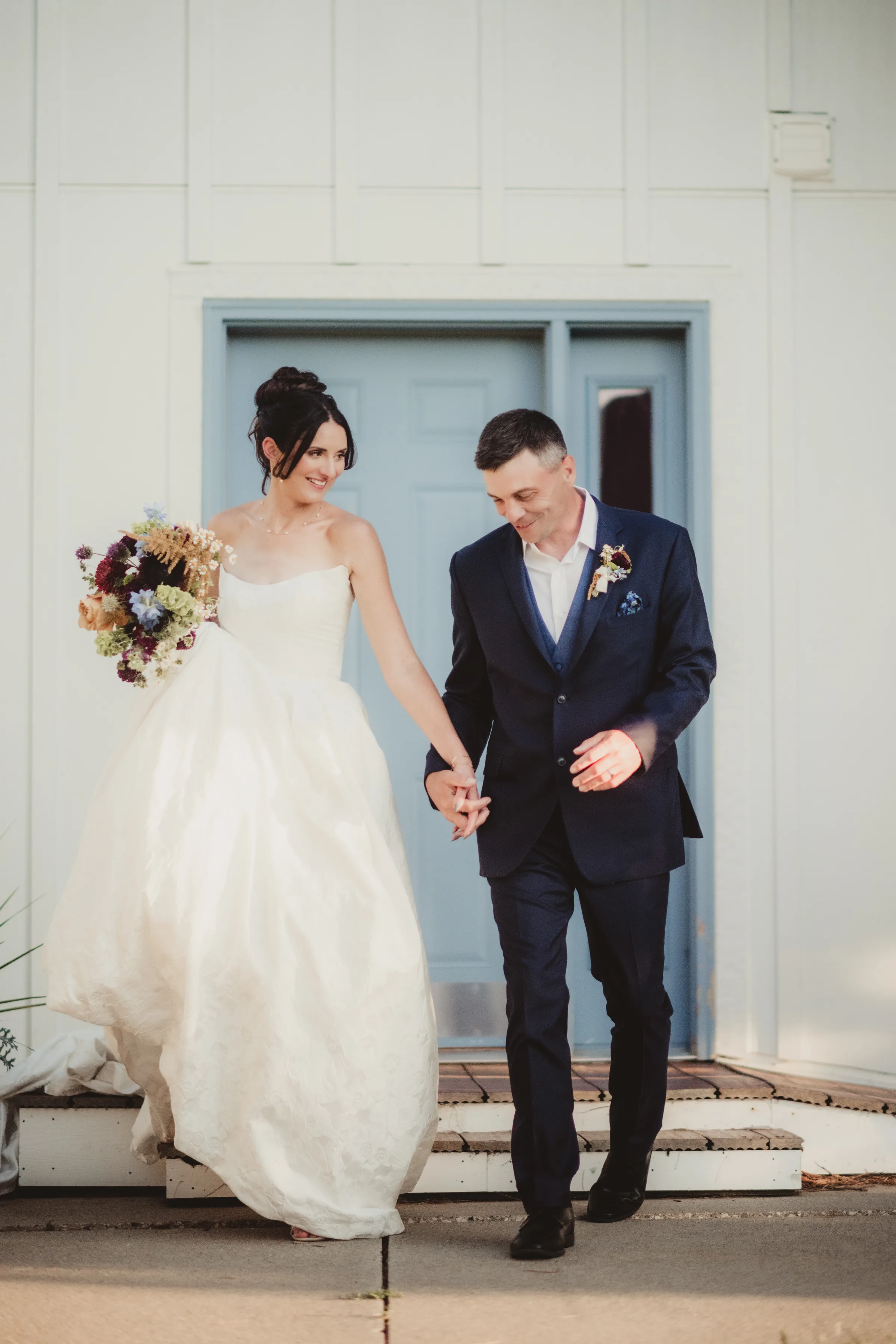 the couple walks towards the camera holding hands