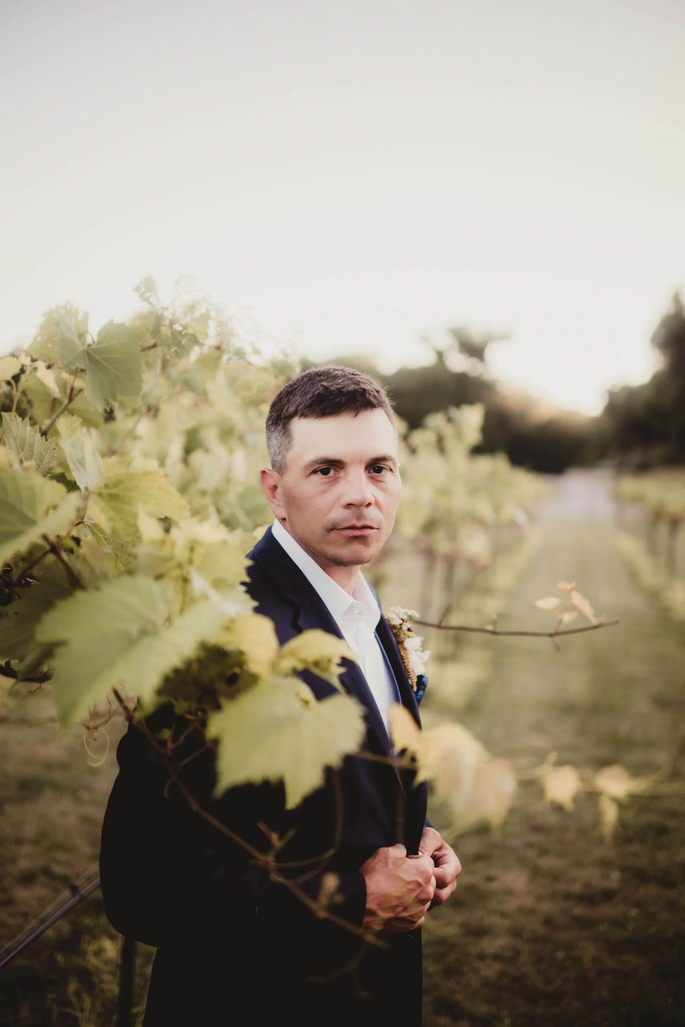 the groom stands in the Vennebu Vineyard
