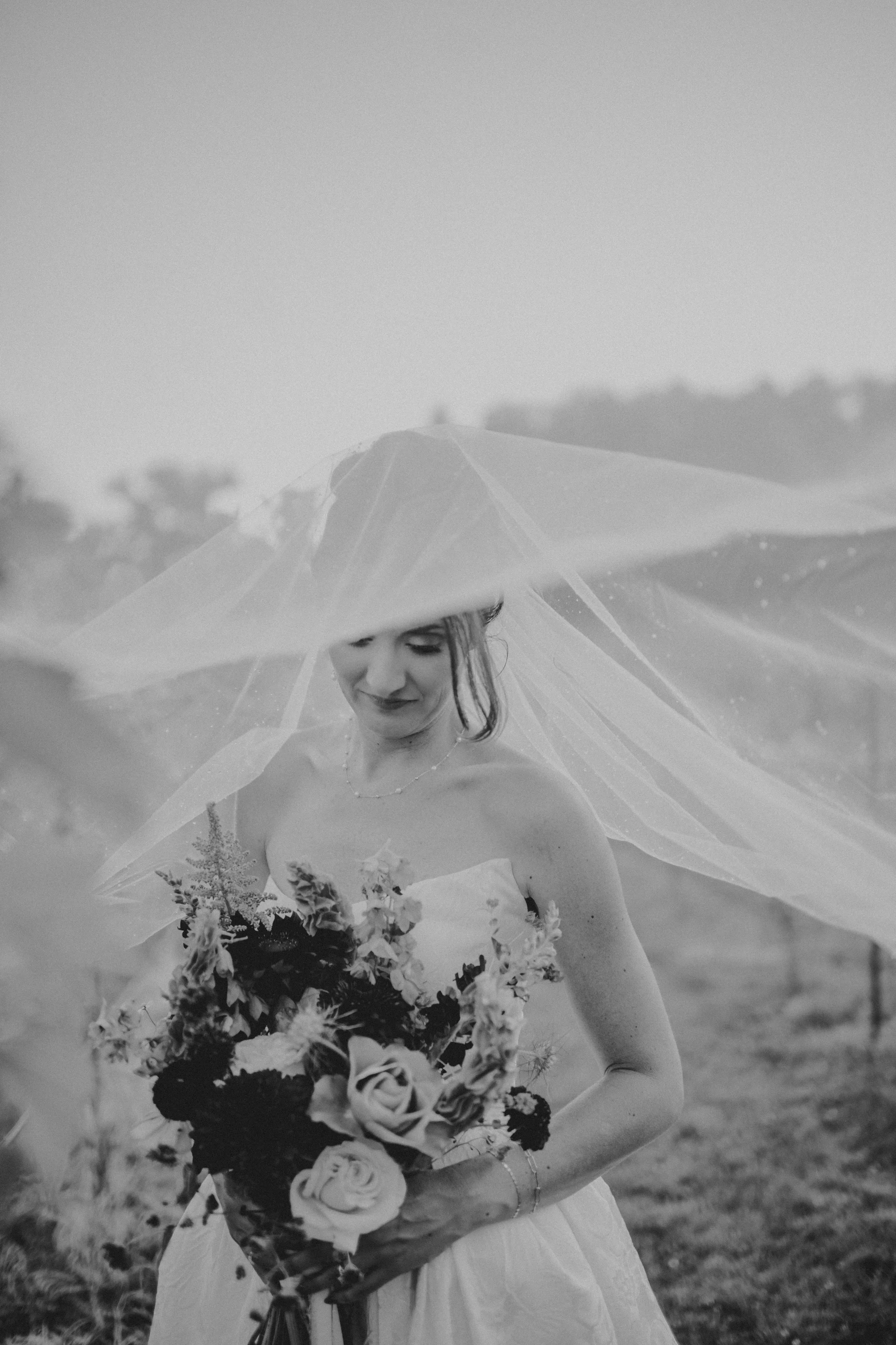 a black and white photo of the bride, with her veil pulled over the camera