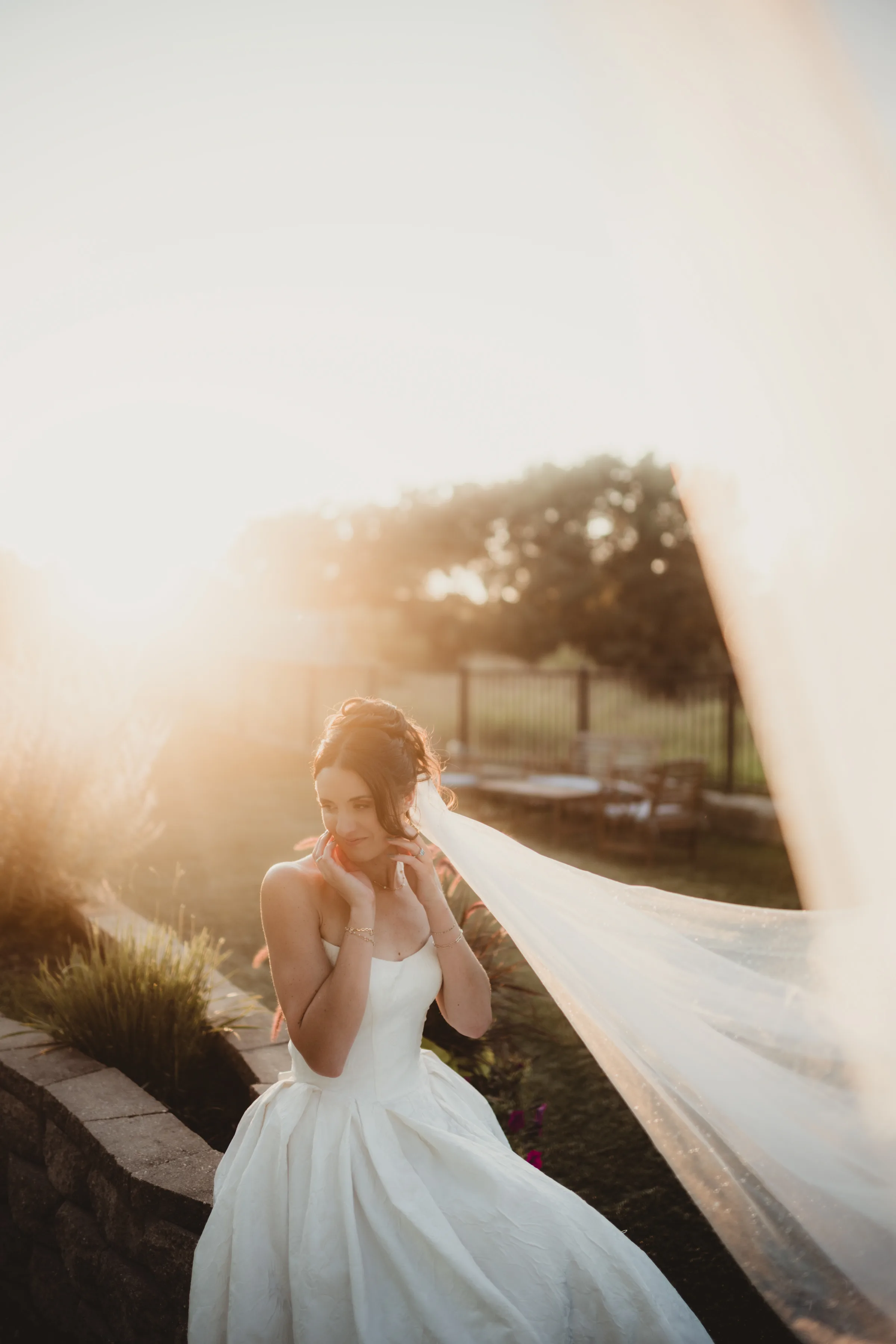 the bride's veil flows in the wind at a portrait during golden hour
