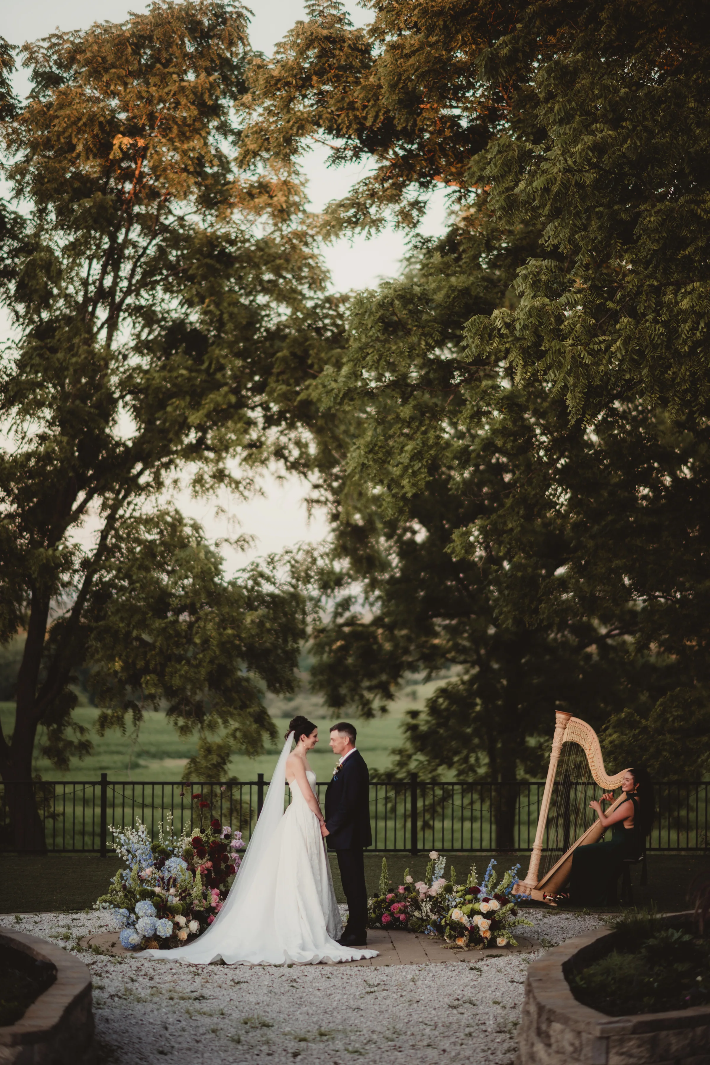 the bride and groom models hold hands in front of a colorful, grounded floral arch wedding inspiration from Signature Events, featuring wildflower styling