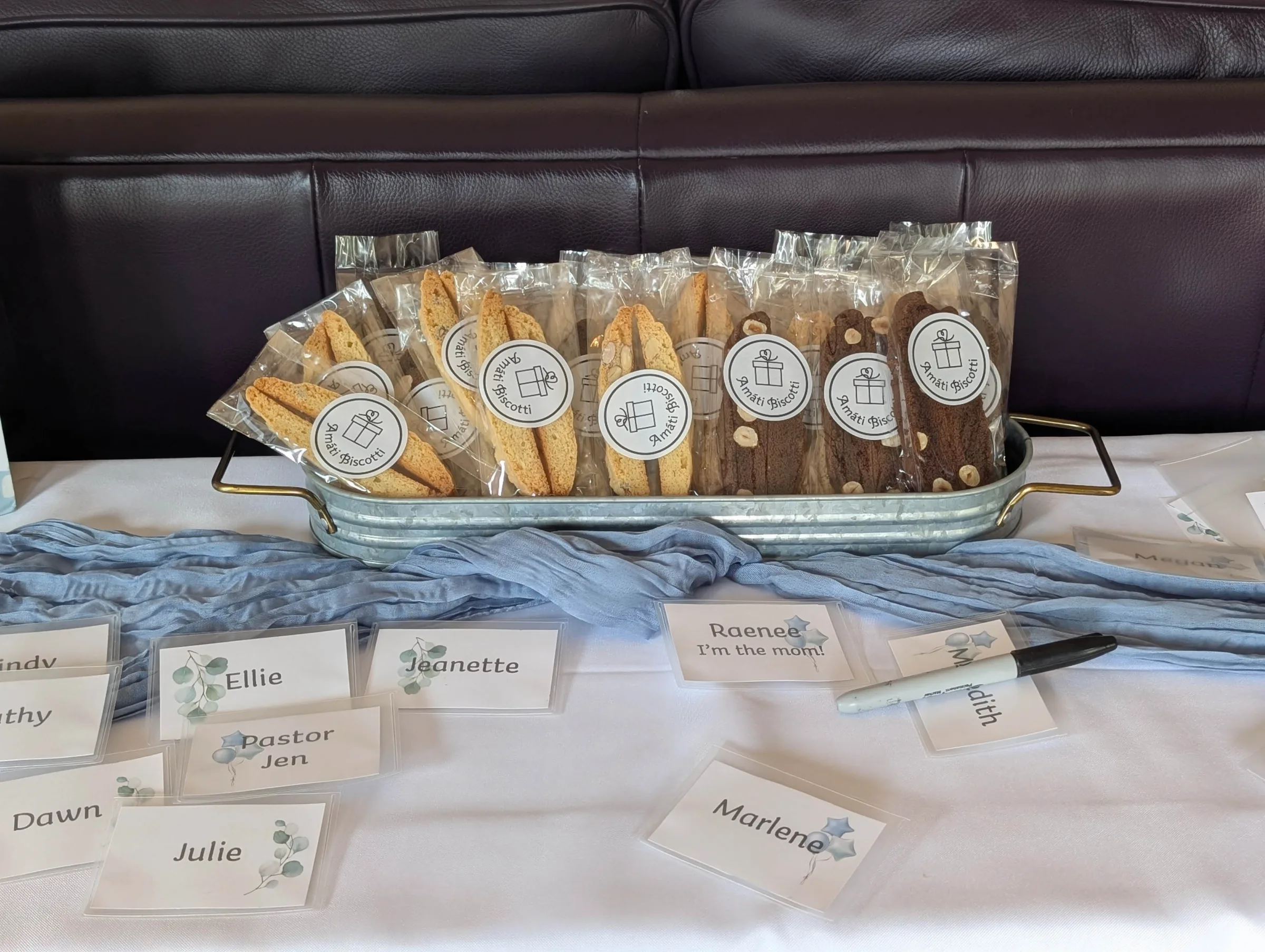 Amati Biscotti wedding favors displayed in a galvanized tray, almond and chocolate hazelnut flavors, alongside guest name cards