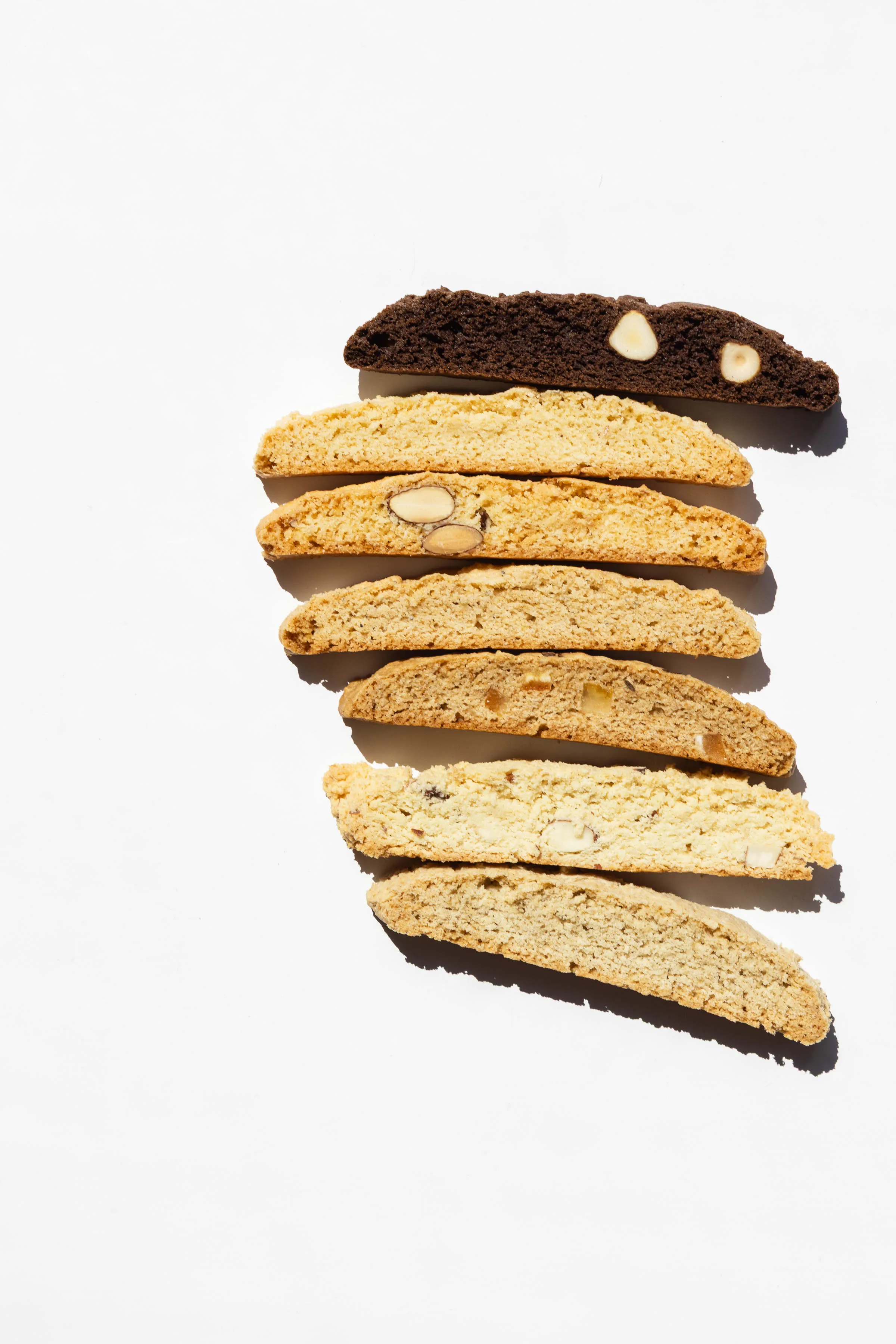 Amati Biscotti flavor lineup — chocolate hazelnut, almond, and fruit and nut biscotti sliced and displayed side by side