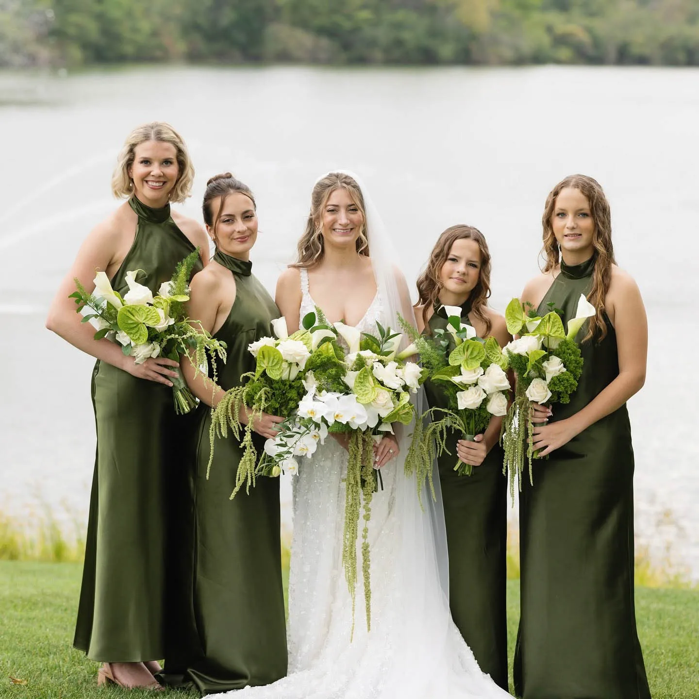 MAIE House hair and makeup for bride and four bridesmaids in olive green gowns, posed together by a lake