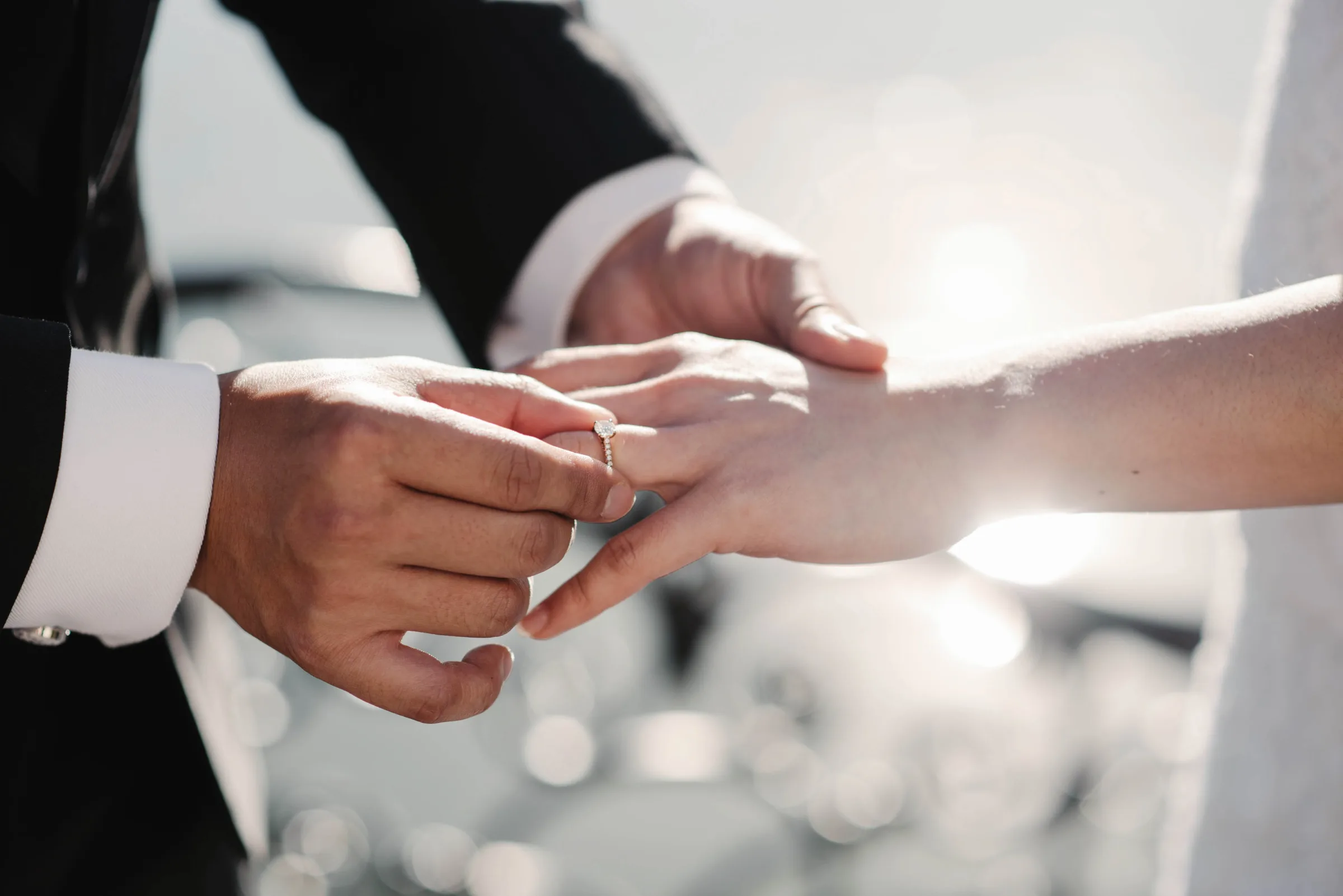 Closeup photo of bride and groom holding golden wedding rings on