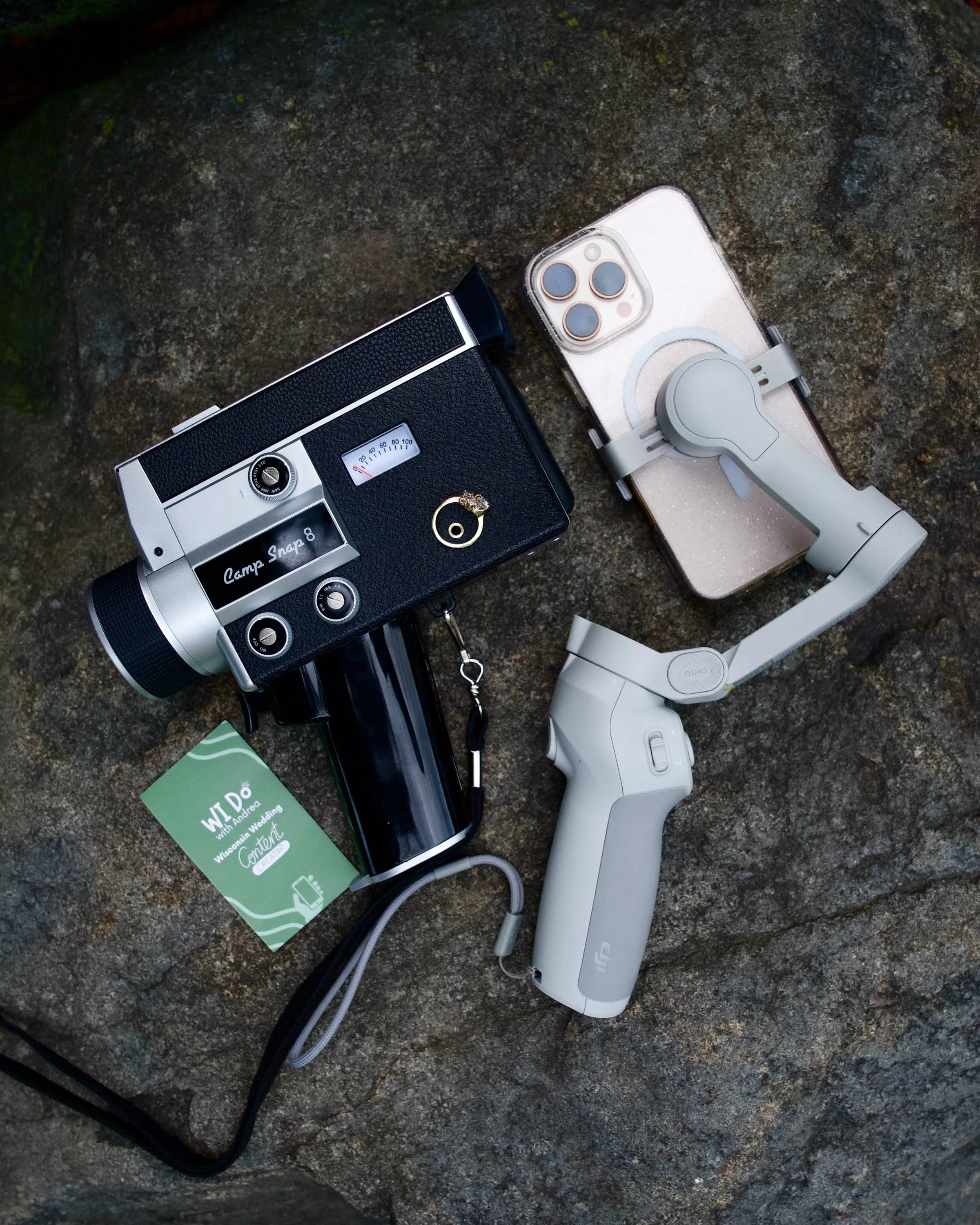 Flat lay of a gimbal with an iPhone and a Camp Snap 8 with wedding rings on it next to a business card that says Wi Do with Andrea Wisconsin Wedding Content Creator