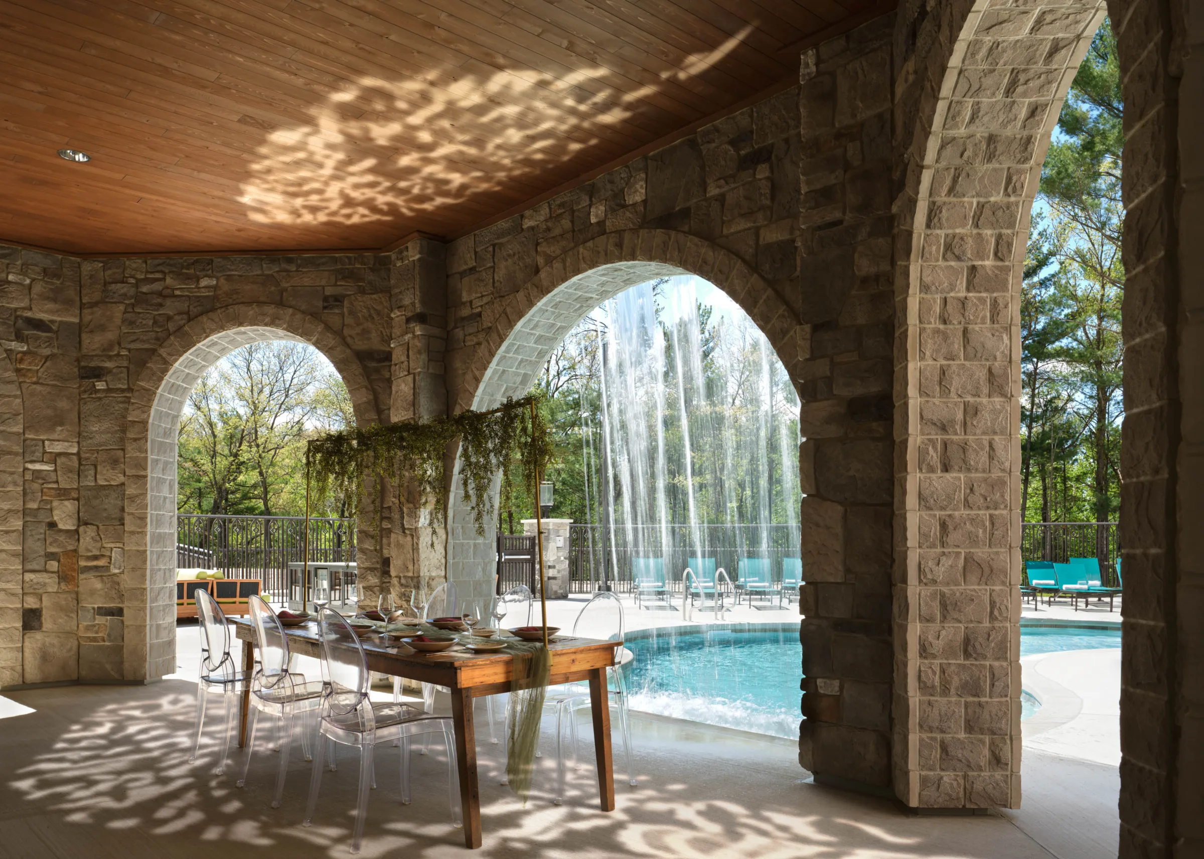 Luxury outdoor wedding reception and private dining venue at Dellshire Resort in Wisconsin Dells, featuring a stone archway patio set with an elegant banquet table next to a pool waterfall.