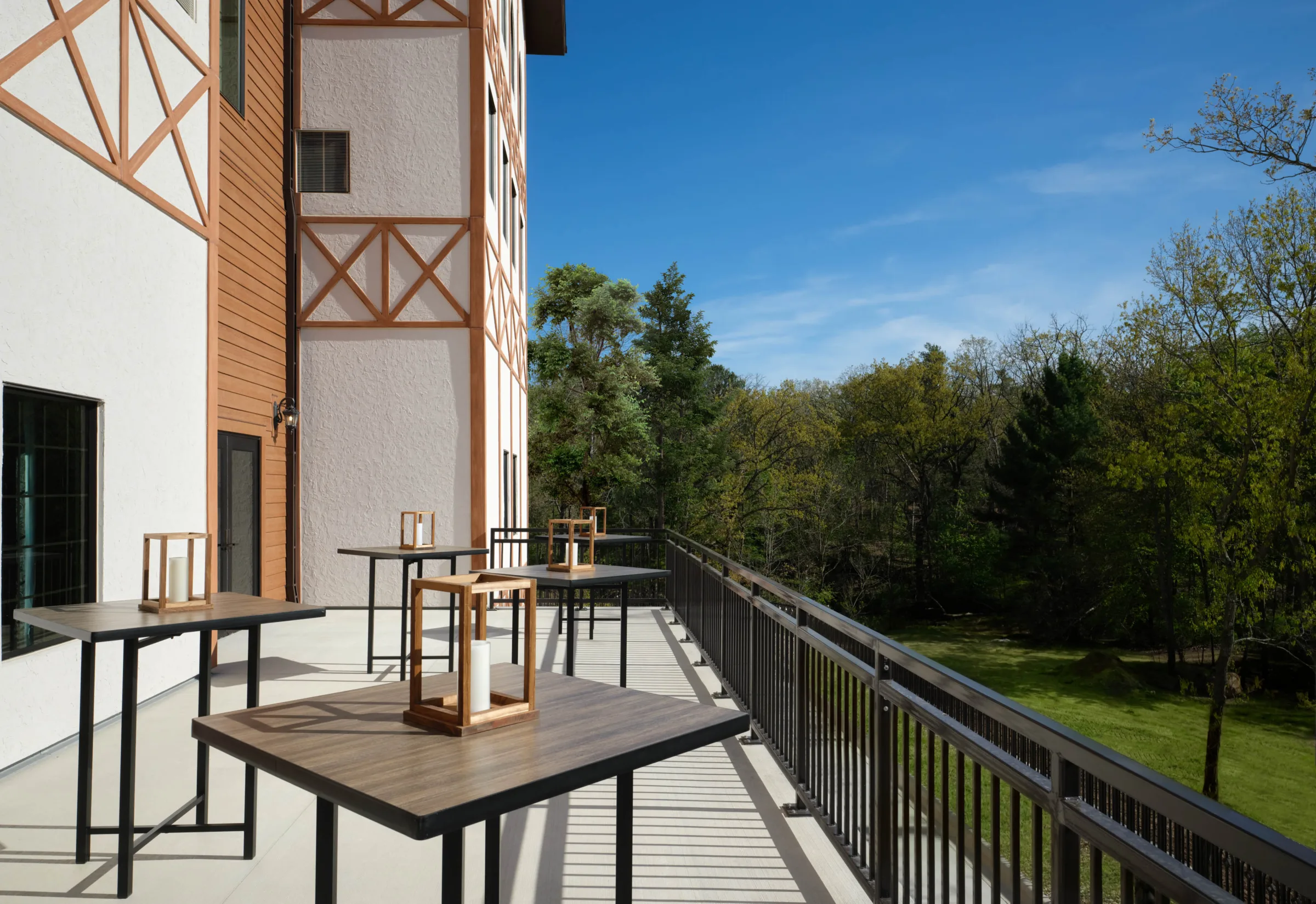 Outdoor wedding cocktail hour patio at Dellshire Resort, a premier Wisconsin Dells wedding venue, featuring high-top reception tables overlooking a wooded forest.