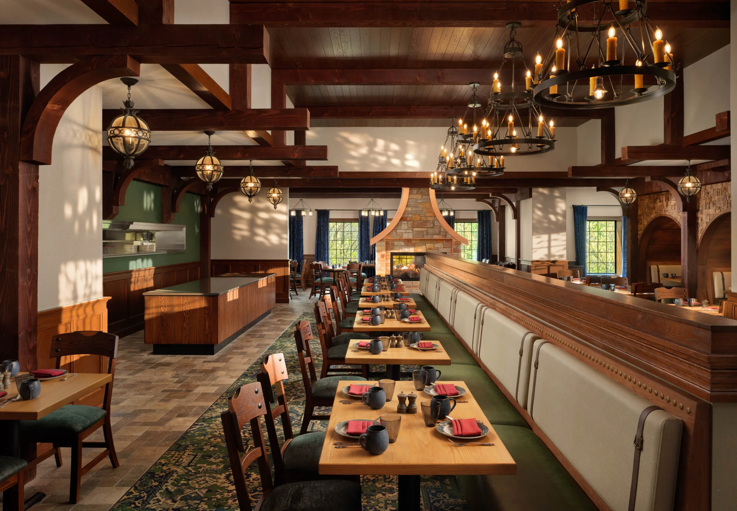 Cozy restaurant interior at Blade & Barrel inside Dellshire Resort, featuring rustic wooden beams, long banquet booths, and a central stone fireplace.